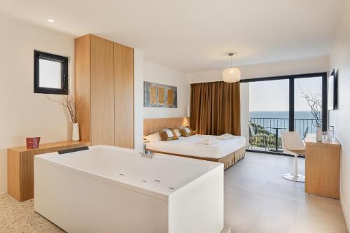 a hotel room with a bed and a bedroom with a tub at Grand Hotel Du Golfe - Spa & Restaurant in Collioure