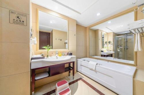 a bathroom with a tub and a large mirror at Country Garden Phoenix Hotel Anqing in Renyuexing