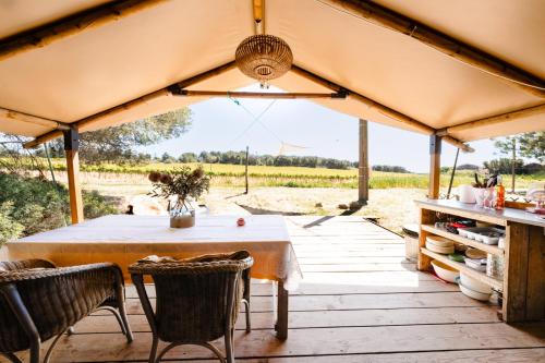 une table et des chaises d'extérieur sous un grand parasol dans l'établissement Saint Paul le Marseillais Tentes Equippees Hébergements Insolites Lodges, à Mèze