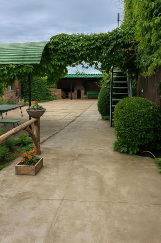 a patio with a bench and an arch with flowers at Helena guest house in Cholpon-Ata
