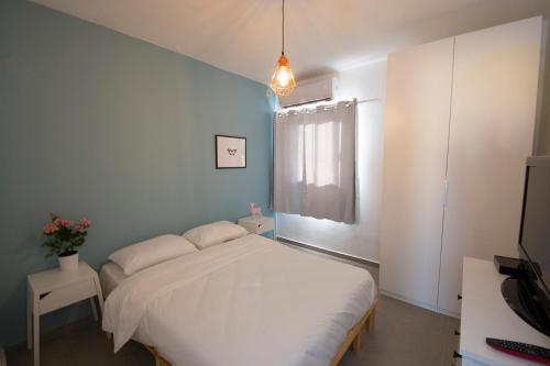a bedroom with a white bed and a blue wall at Holiday Apartment Alona in Eilat