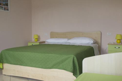 a bedroom with a bed with a green blanket and pillows at B&B L'Angolo in Sannicola