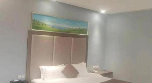a bedroom with a bed with a painting above it at Jie Hao Royal Hotel in Shenzhen