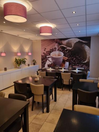 a restaurant with tables and chairs and a painting on the wall at Hotel Café de Sport in Velden