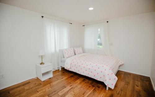 a white bedroom with a pink bed and a window at SeaTac place in SeaTac