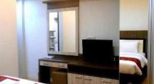 a bedroom with a bed and a dresser with a mirror at Grant Hotel Subang in Bandung