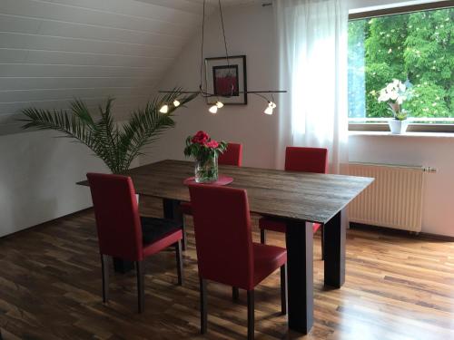 a dining room with a wooden table and red chairs at Apartment Rose in Ahausen