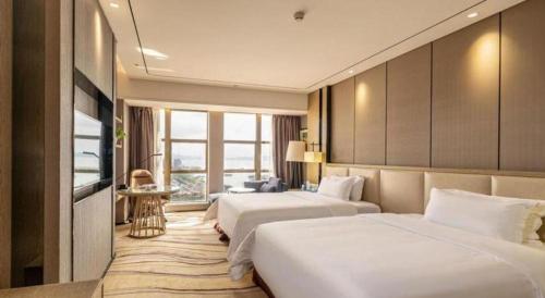 a hotel room with two beds and a television at Clear Lake Hotel in Shanwei