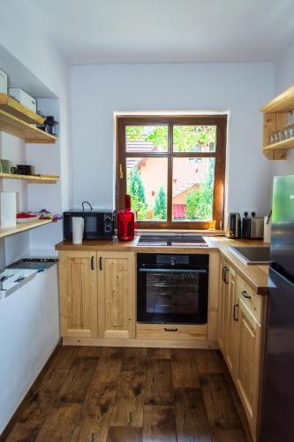 a kitchen with wooden cabinets and a window at Jókai Guesthouse in Tuşnad