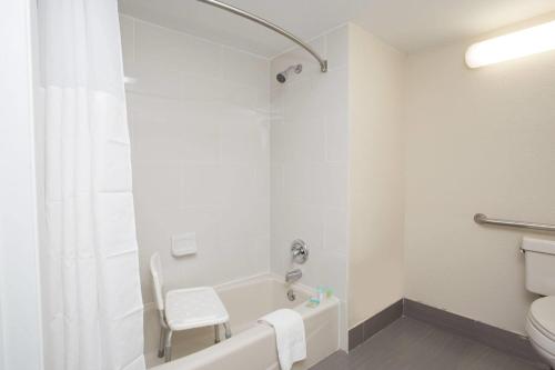 a bathroom with a white tub and a toilet at Days Inn & Suites by Wyndham Orlando Airport in Orlando