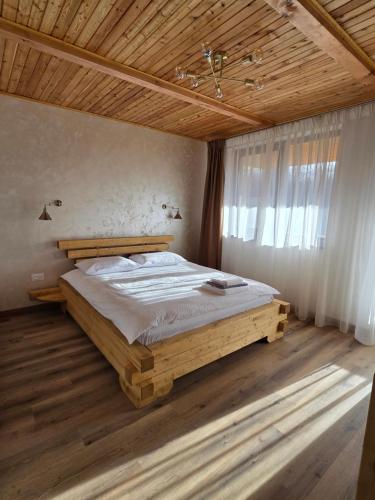 Una cama de madera en un dormitorio con techo de madera. en Complexul Rustic, en Avrig