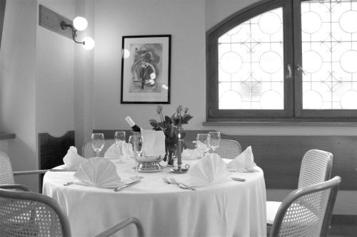 einen Tisch mit einem weißen Tischtuch und Stühlen sowie ein Fenster in der Unterkunft Hotel Centro in Torre Pellice