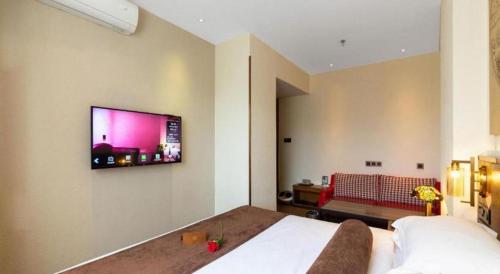 a bedroom with a bed and a tv on the wall at James Joyce Coffetel Xi'an Lingtong The Terracotta Army Huaqingchi University Town Metro Station in Xi'an