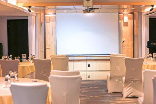a room with tables and chairs and a projection screen at The Grandmark Dhaka in Dhaka