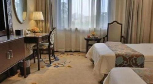 a hotel room with a bedroom with a desk and a bed at Jin Jiang Nanjing Hotel in Nanjing