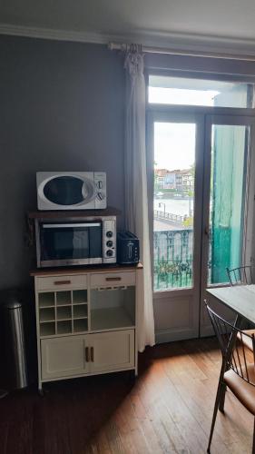 un micro-ondes posé sur un support dans une pièce avec une fenêtre dans l'établissement Cozy french apartment with a beautiful view, à Agde