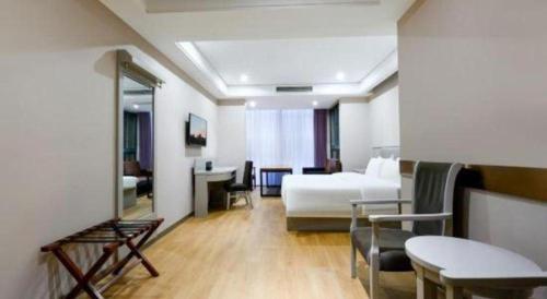 a hotel room with a bed and a table and chairs at GreenTree Inn Fuyang Yijing International North Business in Fuyang