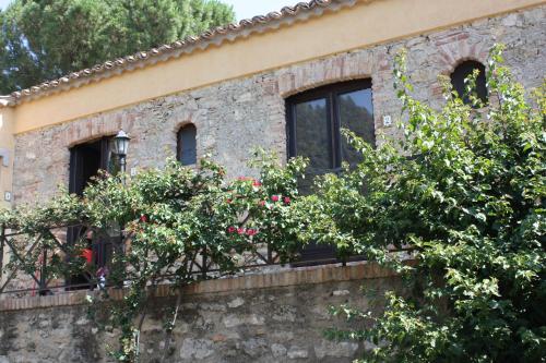 a house with windows and roses on a stone wall at Azienda Agrituristica Le Puzelle in Santa Severina