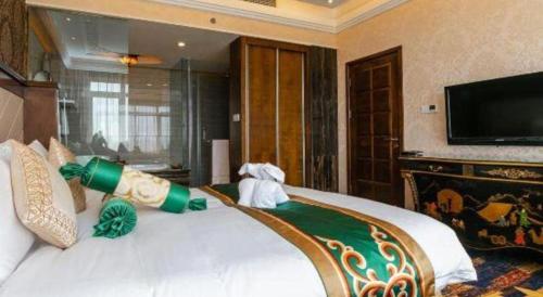 a bedroom with a large white bed with a flat screen tv at Hohhot Inner Mongolia Hotel in Hohhot