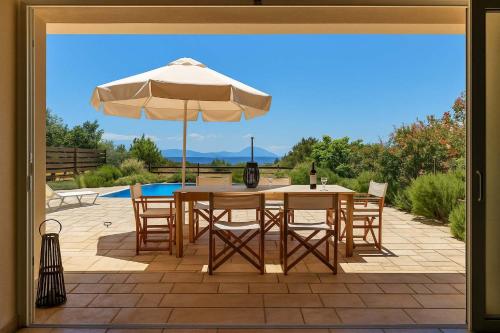 a patio with a table and an umbrella at Seaside Aqua Bliss & Serenity with Private Pool in Koilás