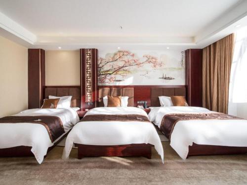 three beds in a room with a painting on the wall at GreenTree Inn Kunming Baiyun Road Tongde Plaza Branch in Kunming