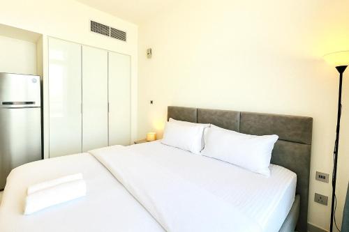 ein Schlafzimmer mit einem Bett mit weißen Laken und einem Kühlschrank in der Unterkunft Dezire Delight in Dubai