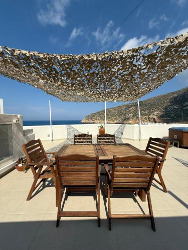 a wooden table and chairs on a patio with the beach at white house apollon naxos in Apollon