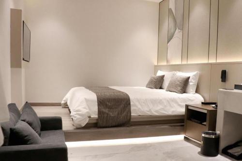 a white bedroom with a bed and a chair at Taiyi International Hotel in Wenzhou
