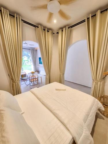 a bedroom with a white bed and a window at Mersika Dua - Beachfront Villa 2BR Near To Mersing Jetty Town in Mersing
