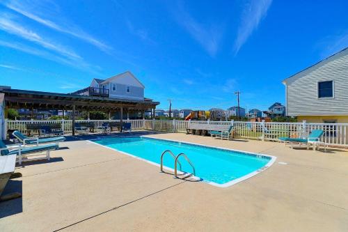a swimming pool with two chairs and a house at 7144 - Dolphin Lookout ( formerly Sabah Vacations) in Wanchese