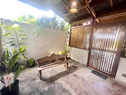 a wooden bench in a room with plants and a wall at Isla Stays Siargao in General Luna
