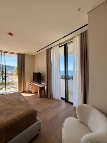 a hotel room with a bed and a couch and windows at Amarea Boutique Hotel in Dhërmi