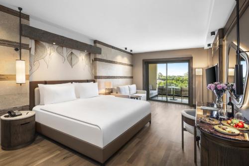 a bedroom with a large white bed and a desk at Kempinski Hotel The Dome Belek in Belek