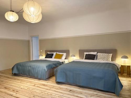 Dos camas en una habitación grande con dos lámparas. en Henrietes Apartamenti, en Kuldīga