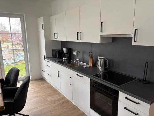 a kitchen with white cabinets and a black counter top at Gartenstraße 22 Haus E Wohnung DG in Stick