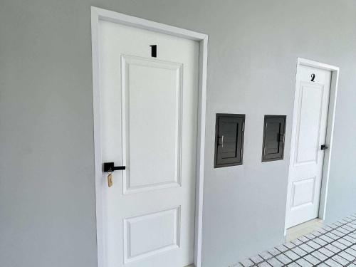 a white door in a white room with two pictures at นราพฤกษา อพาร์ทเมนท์ 
