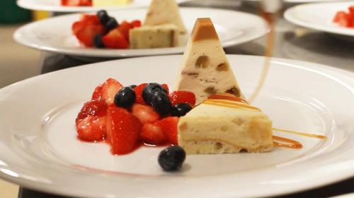 a piece of cake with fruit on a white plate at MUNTE - Wellnesshotel am Stadtwald in Bremen