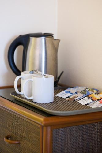 two coffee mugs sitting on a table with a coffee pot at Aquarius On The Beach in Nadi