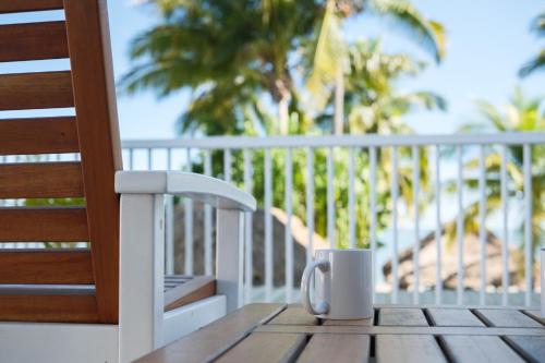 a coffee cup sitting on a wooden table on a balcony at Aquarius On The Beach in Nadi