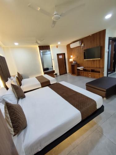 a hotel room with two beds and a television at Hotel Shivtara in Nānded