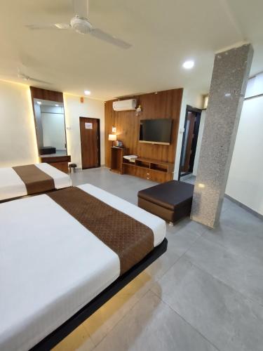 a large bedroom with a large bed and a television at Hotel Shivtara in Nānded