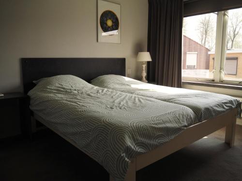 a bed sitting in a bedroom with a window at Ruim appartement met dakterras in Hulst