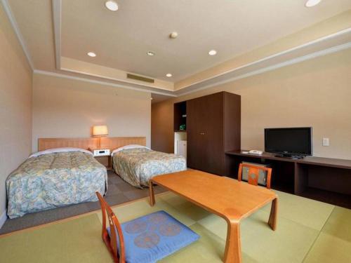 a hotel room with two beds and a desk at Oze Iwakura Resort Hotel in Tokura