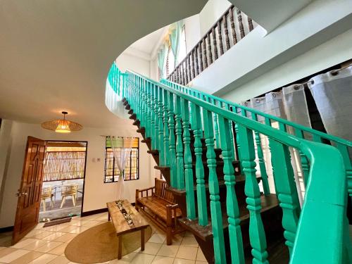 a staircase in a house with a green railing at Isla Stays Siargao in General Luna