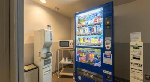 a vending machine in a room with a refrigerator at Alpha Hotel Tokushima in Tokushima