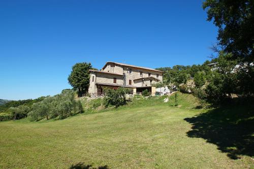 una casa in cima a una collina con un campo di La Valle dei Fiori di Bellucci Rosanna a Torre deʼ Calzolari