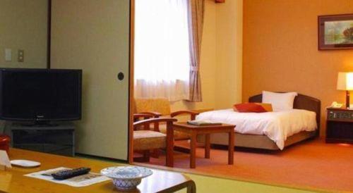 a living room with a bed and a tv in a room at Kyoto Keburikawa Hotel in Kameoka