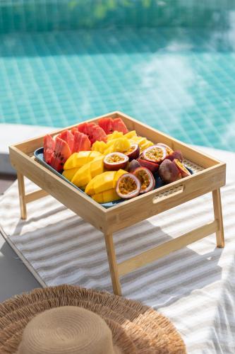 a tray of fruit on a table next to a pool at Caya Beach by Satori in Koh Phangan
