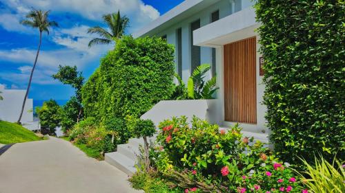 a house with plants and flowers next to a walkway at Anzhu Seamate Villa Samui in Amphoe Koh Samui