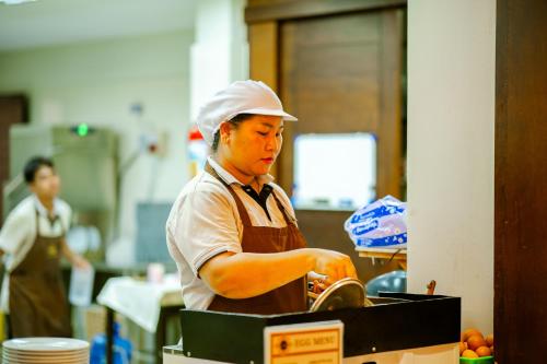 a person in a kitchen preparing food at Am Samui Palace in Lamai